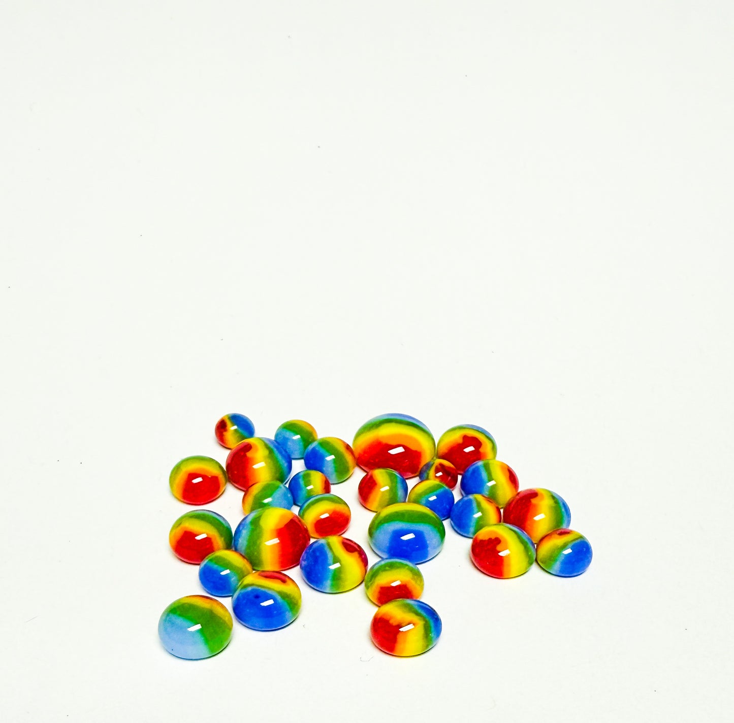 Assorted rainbow glass dots made from Oceanside COE 96 glass arranged on a white background.